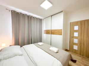 a white bedroom with two beds and a window at Simcity V I City center,garage,balcony & self check-in in Banská Bystrica