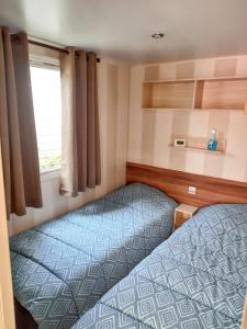 2 Betten in einem kleinen Zimmer mit Fenster in der Unterkunft Bungalow de 2 chambres a Valras Plage a 200 m de la plage avec piscine partagee et terrasse in Valras-Plage