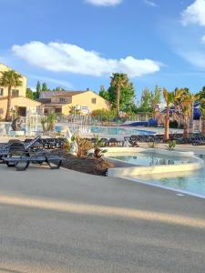 einen Pool in einem Resort mit Tischen und Stühlen in der Unterkunft Bungalow de 2 chambres a Valras Plage a 200 m de la plage avec piscine partagee et terrasse in Valras-Plage