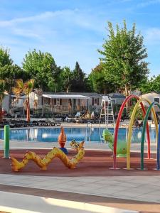 einen Spielplatz vor einem Pool in der Unterkunft Bungalow de 2 chambres a Valras Plage a 200 m de la plage avec piscine partagee et terrasse in Valras-Plage