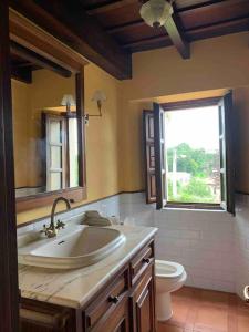 a bathroom with a sink and a toilet and a window at Casa La Bolera Casa de dos plantas porche y jardín in Llanes