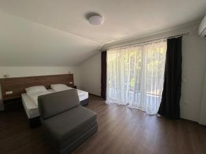 a bedroom with a bed and a chair and a window at Villa Forest Ohrid in Peštani