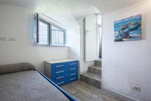 a bedroom with a bed with a blue dresser and a window at Appartamento con vista esclusiva sul Golfo d'Ischia in Ischia