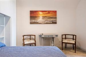 a bedroom with a bed and two chairs and a desk at Appartamento con vista esclusiva sul Golfo d'Ischia in Ischia