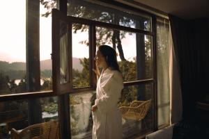 een vrouw in een badjas die uit een raam kijkt bij Boutique Hotel & Spa Bosque del Nahuel in Bariloche