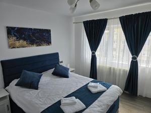 Un dormitorio con una cama con almohadas azules y una ventana. en Emiri Apartament, en Hunedoara