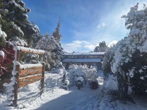 a snow covered garden with a sign and trees at Bungalows Luz del sur in San Carlos de Bariloche