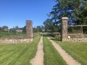 Un antiguo muro de piedra con dos torres en un campo en La Canuche Appartement avec jardin, en Pleine-Sève