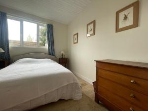 Un dormitorio con una cama y una cómoda y una ventana. en La Canuche Appartement avec jardin, en Pleine-Sève