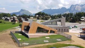 a large building on a field with mountains in the background at La TANIÈRE du LOUP in Le Dévoluy