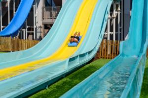 uma criança a brincar num escorrega num parque aquático em Jupiter Albufeira Hotel - Family & Fun - All Inclusive em Albufeira