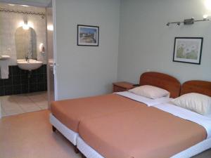 a bedroom with a bed and a bathroom with a sink at Hostellerie La Boheme in Roppenheim
