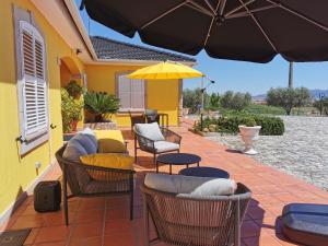 a patio with chairs and tables and an umbrella at A Flor da Rosa in Vila Nova de Foz Coa