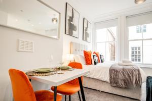 a bedroom with a bed and a table with orange chairs at Guest Homes - The Station Studio in Worcester