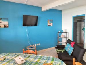 ブイヤントにあるAppartement d'une chambre avec vue sur la mer terrasse amenagee et wifi a Bouillante a 4 km de la plageの青い壁のベッドルーム(ソファ、テレビ付)