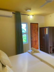 1 dormitorio con 1 cama con ventana y espejo en White Sand Inn, en Maamigili
