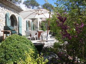 a patio with a table and chairs and an umbrella at L'Ostal du Pic St Loup in Saint-Jean-de-Cuculles