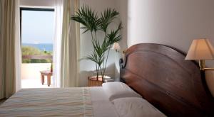 a bedroom with a bed and a window with a plant at Hotel Mediterraneo in Santa Maria Navarrese