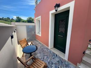 a small balcony with a green door and chairs at Corfusion studio in Alykes Potamou