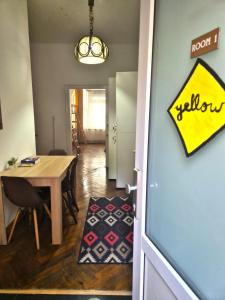 ein Esszimmer mit einem Tisch und ein Raum mit einem gelben Schild in der Unterkunft Centrum House Hostel in Braşov