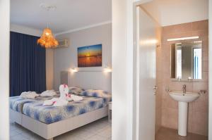 een slaapkamer met een bed, een wastafel en een badkamer bij Hotel Tigaki's Star in Tigaki