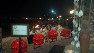 un groupe de personnes assises sur des chaises dans un restaurant la nuit dans l'établissement Tortuga beach resort Penthouse apartment for holiday rental, à Prainha
