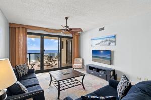 Una sala de estar con un sofá, un televisor y una mesa. en Romar House Unit 506A, en Orange Beach
