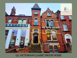 an old brick building with a clock tower on it at Lil Victorian Classic Group Home in Leeds