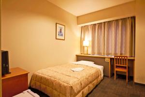 a hotel room with a bed and a desk and a window at Ageo Tobu Hotel in Ageo