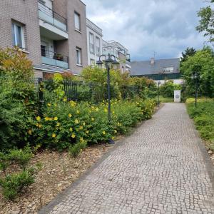 a brick path in front of a garden with flowers at T2 Paris Disneyland Jardin Parking in Noisy-le-Grand