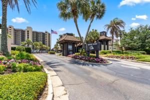 Una calle en el complejo con un cartel y palmeras. en Romar House Unit 506A, en Orange Beach