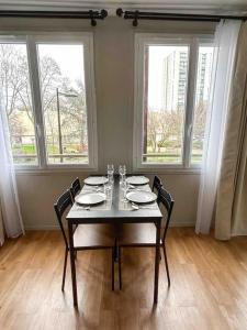 a dining room with a table with chairs and windows at Charmant T2 aux portes de Paris in Aubervilliers