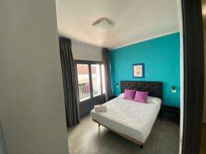 1 dormitorio con paredes azules y 1 cama con almohadas rosas en Agi Macià Centro, en Roses