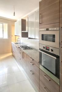 eine Küche mit Küchengeräten aus Edelstahl und Holzschränken in der Unterkunft 2 bedrooms apartement with balcony at Nouaseur in Nouaseur