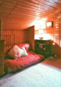 Habitación con sofá rojo en una habitación de madera en Maison de 3 chambres avec vue sur le lac et jardin clos a Talloires Montmin, en Angon