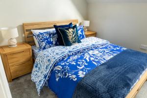 uma cama azul com lençóis e almofadas azuis e brancos em Luxury Apartments - MBS Lettings em Bewdley