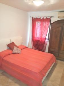 1 dormitorio con cama roja y ventana en One bedroom apartement with sea view enclosed garden and wifi at Olbia 6 km away from the beach, en Alhaurín de la Torre