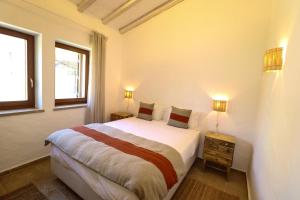 a bedroom with a large bed and two windows at Aldeamento Turistico da Prainha in Alvor