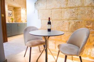 a table with two chairs and a bottle of wine at San Anton Suites in Attard
