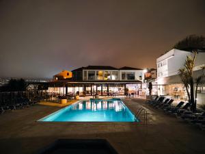 una piscina con sillas y un edificio por la noche en Miramar Hotel Spa & Apartments, en Nazaré