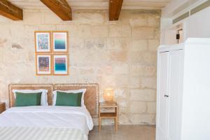 a bedroom with a bed with white sheets and green pillows at San Anton Suites in Attard