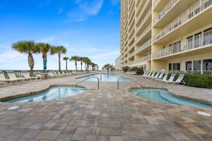 einen Pool in einem Resort mit Stühlen und Palmen in der Unterkunft Newly Renovated Luxury OCEAN FRONT Condo! Top Floor Condo with PENTHOUSE OCEAN VIEWS! in Panama City Beach