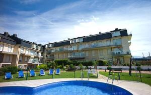 a large apartment building with a swimming pool and blue chairs at Apartamento en Playa de Altar in Barreiros