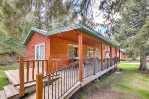 a wooden cabin with a large porch in a forest at Pets Welcome Cozy Cabin with Deck in Deadwood! in Deadwood