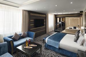 a hotel room with a large bed and a couch at Mövenpick Hotel Qassim in Buraydah