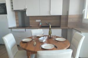 un tavolo in legno con sedie bianche e una bottiglia di vino di Touquet apartment facing the sea a Le Touquet-Paris-Plage