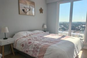 una camera da letto con un letto e una grande finestra di Touquet apartment facing the sea a Le Touquet-Paris-Plage
