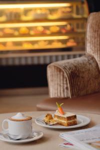 uma chávena de café e um pedaço de bolo numa mesa em Mövenpick Hotel Qassim em Buraydah