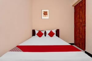 um quarto com uma cama com almofadas vermelhas em OYO Dhanam Lodge em Coimbatore