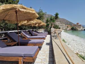 a row of lounge chairs under an umbrella on a beach at Ktima Zaxarias in Kokkala